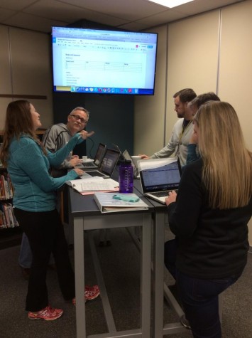 Members of the English department collaborating over the standing tables.