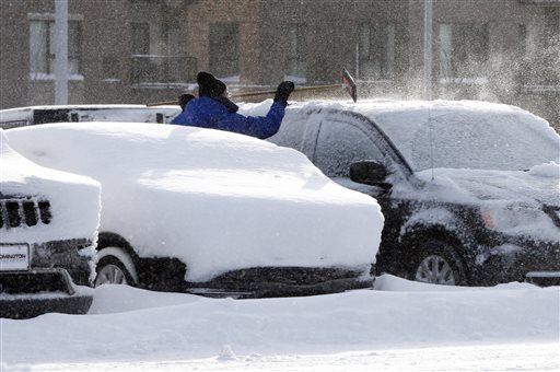 A car dealership employee cleans off a vehicle, Wednesday, Feb. 3, 2016, following a snowstorm which dumped a foot of snow in Southern Minnesota. (AP Photo/Jim Mone)