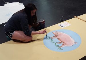 Emma Sackett painting the background set for The Enchanted Pig