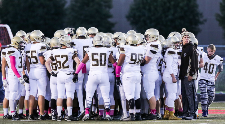 The football team gathers into a huddle during a game.