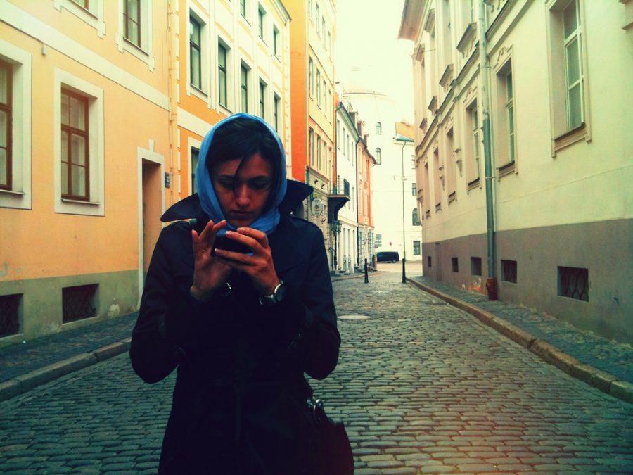 A student absorbed into her phone while walking on the street. 