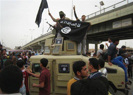 Islamic State group militants hold up their flag as they patrol in a commandeered Iraqi military vehicle in Fallujah, 40 miles west of Baghdad, Iraq. 