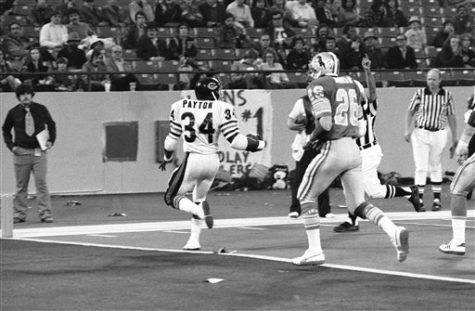 Chicago Bears Walter Payton (34) backs into the end zone and looks back at Detroit Lions Dick Jauron (26) in the fourth quarter of Thanksgiving Day game, Thursday, Nov. 24, 1977 in the Pontiac Silverdome. Chicago defeated the lions, 31-14. (AP Photo)