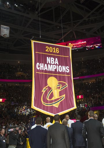 Cleveland Cavaliers players and executives watch as the championship banner is raised before a basketball game against the New York Knicks in Cleveland, Tuesday, Oct. 25, 2016. (AP Photo/Phil Long)