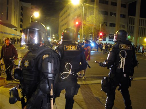 FILE- In this March 30, 2014 file photo, riot police stand guard near a crowd protesting police shootings in Albuquerque, N.M. As this city of 550,000 continues to see public demonstrations over a rash of police shootings, activists say they are looking to New Mexicos history of resistance and previous protests to draw attention to what they said are major problems within the police department. (AP Photo/Russell Contreras, File)