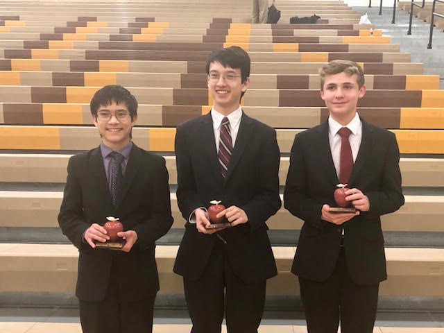 Tai Henrichs, Brandon Schellhaass, and Dallas Mahal smile with their apples in hand.